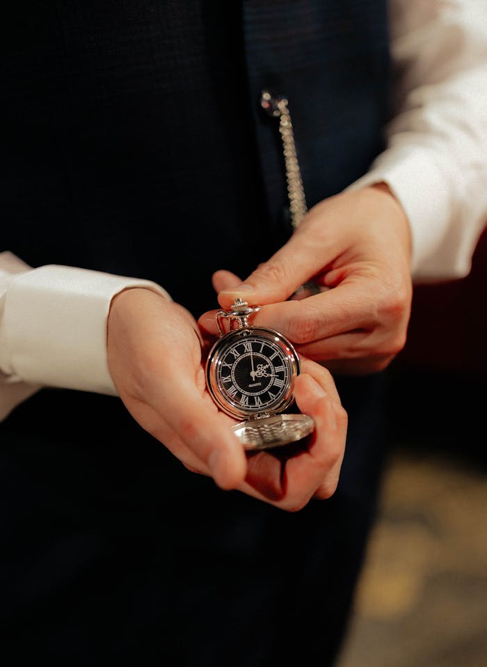 An elegant man displaying a vintage pocket watch, showcasing classic style.