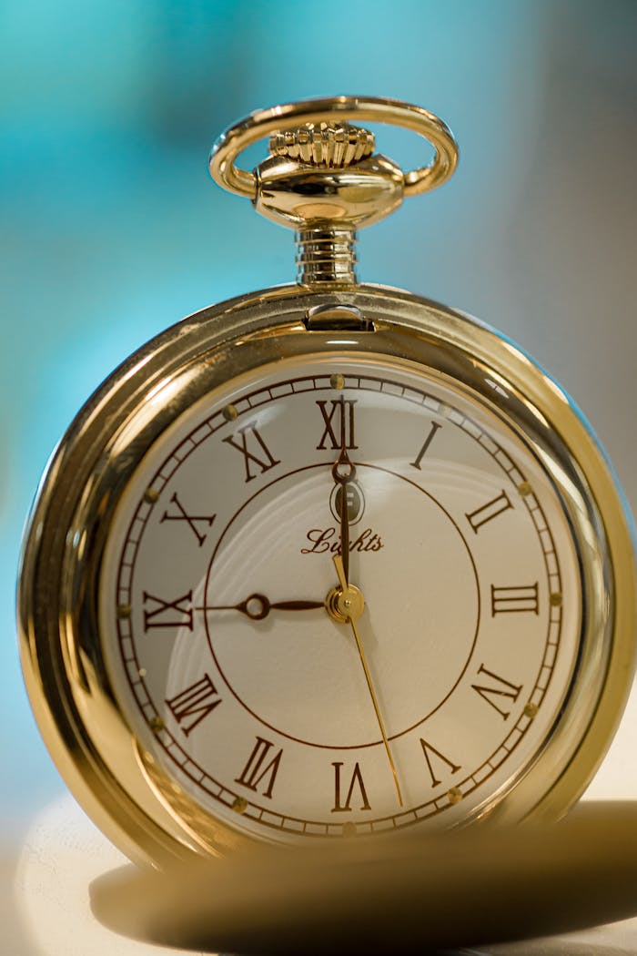 Close-up of an elegant gold pocket watch with Roman numerals, capturing classic style.